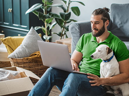 Person sitting with dog on floor of a new apartment where fiberoptic internet is included with lease 